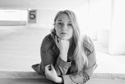 Portrait of young woman leaning on railing at parking lot