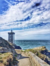 Lighthouse by sea against sky