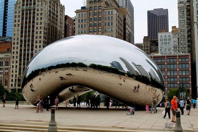 People on street amidst modern buildings in city