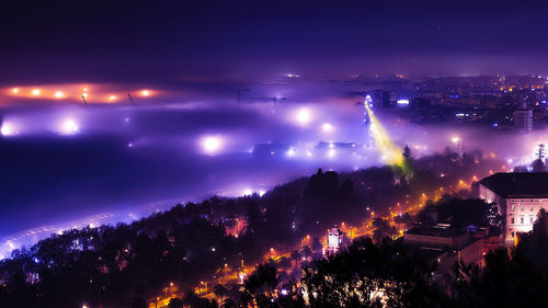 Illuminated cityscape against sky at night