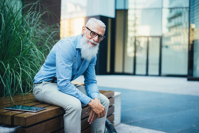 Senior hipster sitting against plants