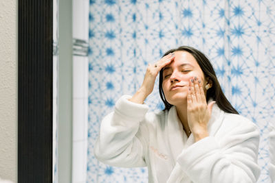 Woman in front of a bathroom mirror massaging her face