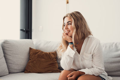 Young woman sitting on sofa at home