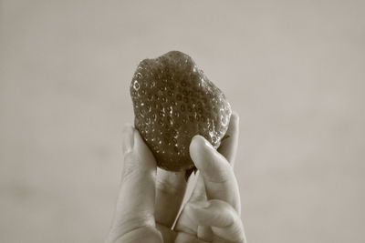 Close-up of hand holding ice cream over white background