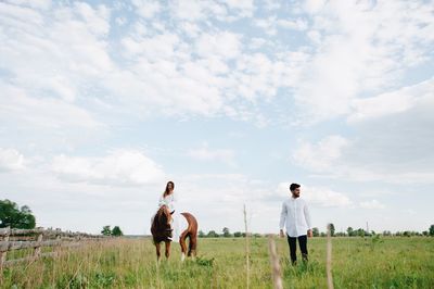 Woman riding horse on field