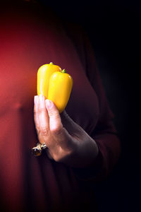 Woman in a tile-colored dress, and yellow peppers in hand