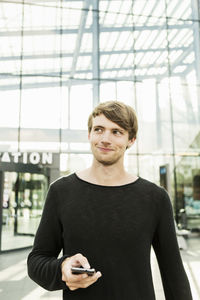 Smiling man looking away while standing outside railroad station