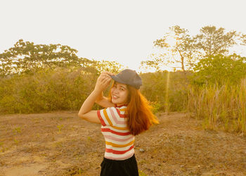 Young woman smiling while standing on land against sky
