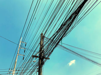 Low angle view of electricity pylon against blue sky