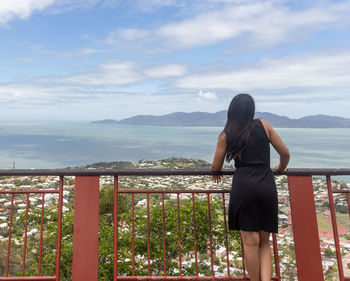 Rear view of woman standing on railing against mountain