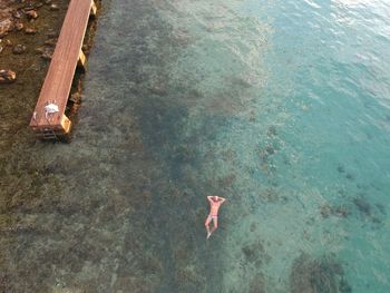 Aerial view of shirtless man swimming in sea