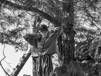 Low angle view of woman standing against tree