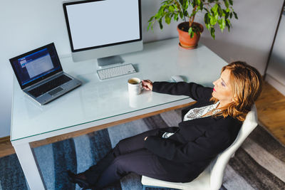 Woman using mobile phone while sitting on table