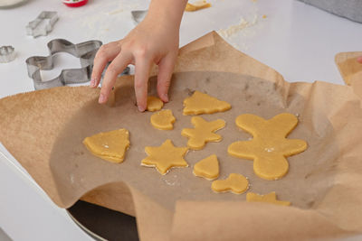 One children's hand lays dough figurines in the form of christmas symbols on parchment