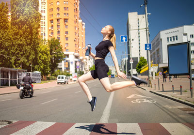 Fitness woman runner silhouette in city on crosswalk.