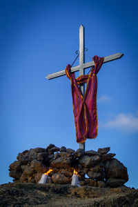 Low angle view of cross on rock against sky