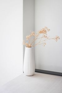 Close-up of white flower vase on table against wall at home
