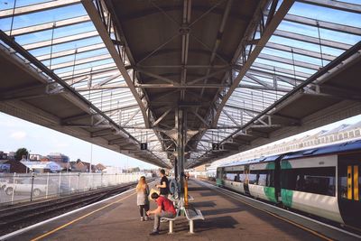 People at railroad station platform against sky