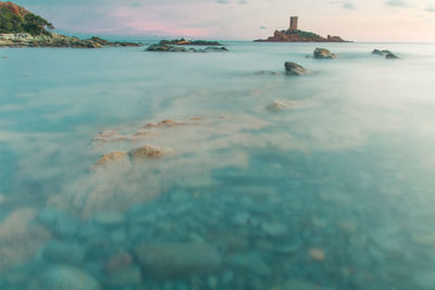 Scenic view of sea and island with castle against sky