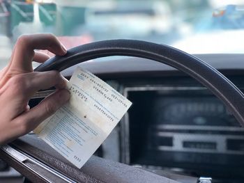 Cropped hand holding receipt in car