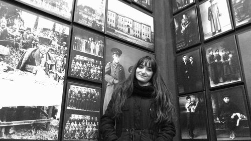 Portrait of smiling young woman standing against window