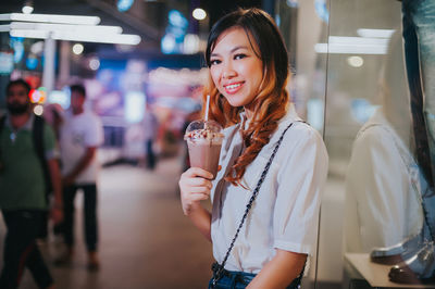 Young woman drinking water from while standing at outdoors