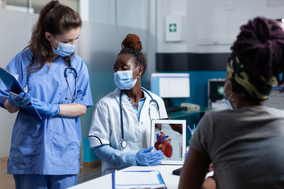 Doctor wearing mask talking with nurse at hospital