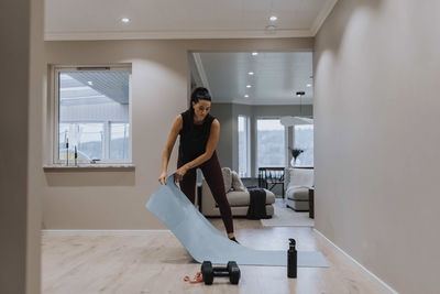 Woman putting exercising mat on floor