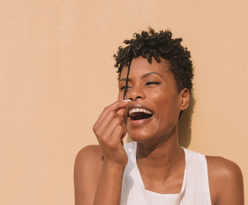 Portrait of smiling young woman standing against wall