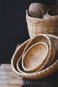 Close-up of wicker baskets on table against black background