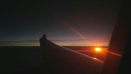 Close-up of airplane wing against sky during sunset