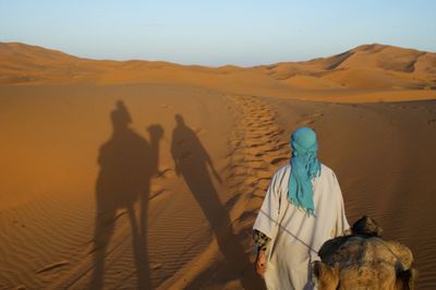 Panoramic view of people riding in desert against sky