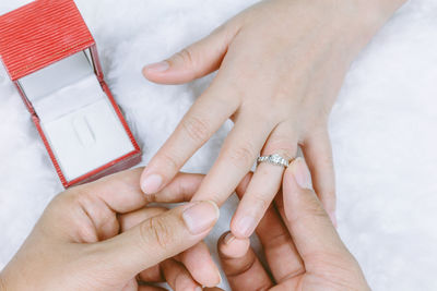 Cropped hands of man inserting diamond ring in woman finger
