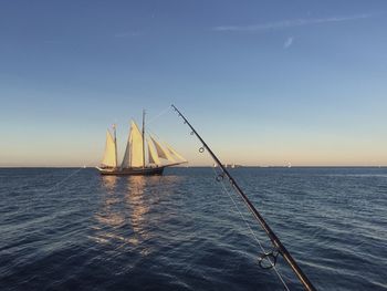 Sailboat sailing on sea against clear sky during sunset