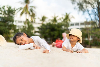 Siblings lying on sand at beach