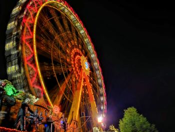 Low angle view of illuminated ferris wheel against sky at night