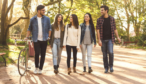 Full length of young friends walking at park