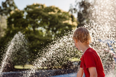 Rear view of boy standing in water