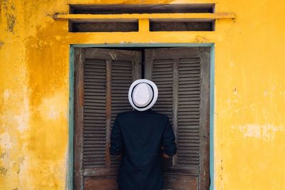 Rear view of man opening door of house