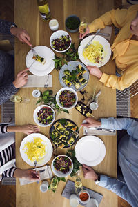 Overhead view of friends eating lunch while sitting at dinning table in party