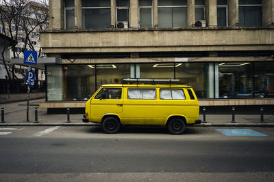 Yellow car parked on street against building