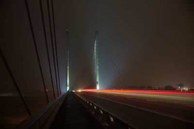 Light trails on road against sky at night