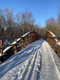 Snow covered footbridge against sky