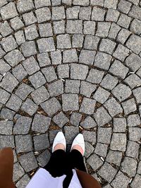 Low section of woman standing on cobblestone street