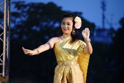 Portrait of smiling young woman standing against sky