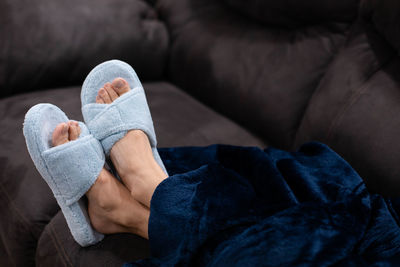 Close up of woman's feet resting on a couch wearing slippers
