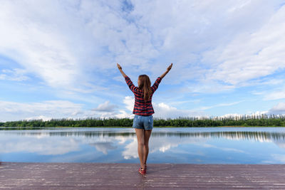 Woman standing by lake against sky