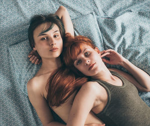 High angle portrait of lesbian couple lying on bed