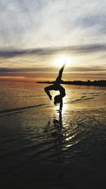 Silhouette woman on beach against sky during sunset