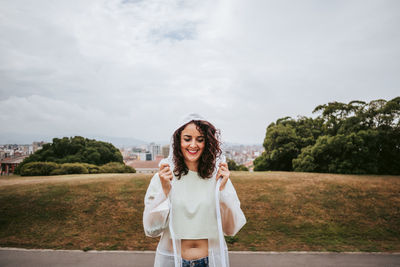 Portrait of smiling young woman standing against sky
